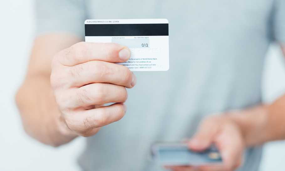 man holding a credit card backwards showing its security code