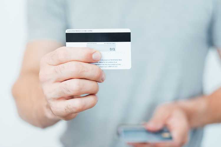 man holding a credit card backwards showing its security code